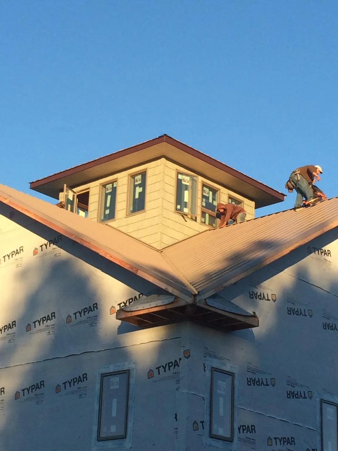 Roofers working around a rooftop cupola on a new metal roof at sunset — Roof Waterproofing in Odessa by Roofing Brothers